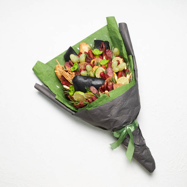 Gift to a man in the form of a bouquet of sausage, cheese, bread, decorated with rosemary, lemon and grapes stock photo