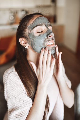 Beautiful Female Applying Dark Skincare Cream On Face After Bath