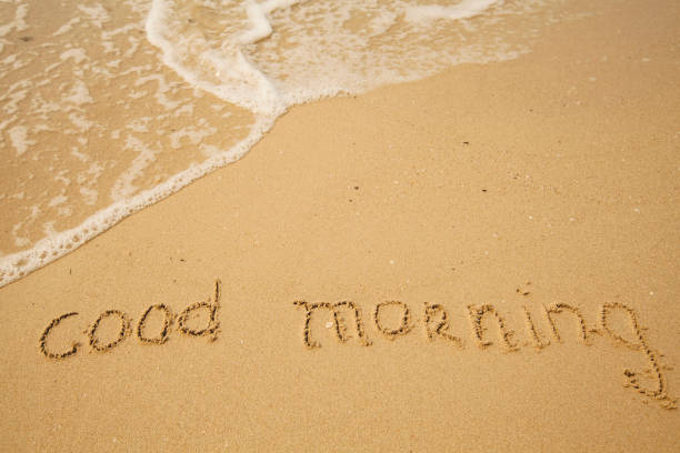 istock Good morning - handwritten on the soft beach sand with a soft lapping wave. 1396486711