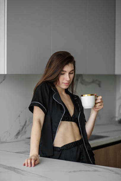 istock Young beautiful woman drinks morning coffee from white cup in kitchen. Rest and weekends. 1396488163
