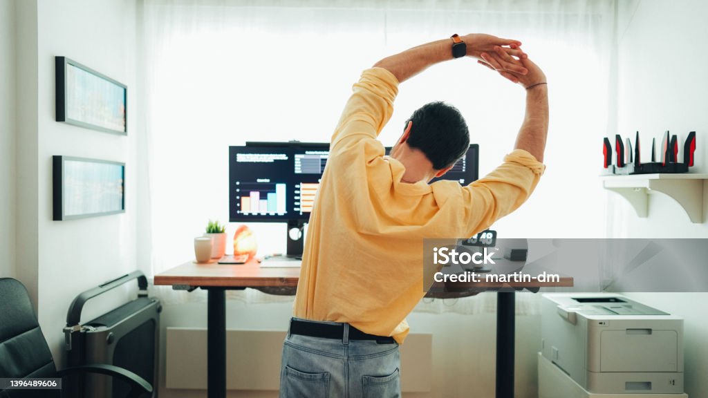 Man working at standing desk Man working at home is stretching Ergonomics Stock Photo