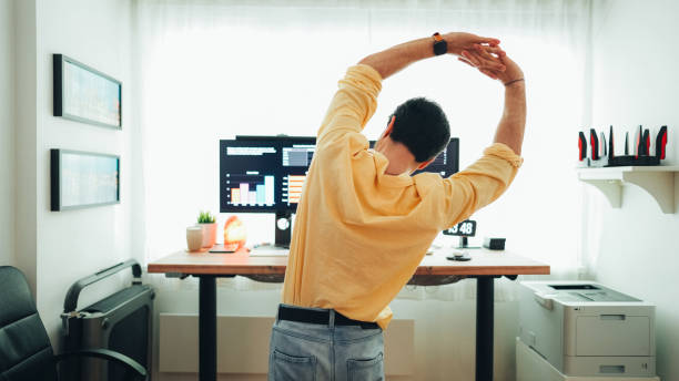 man working at standing desk - esticar imagens e fotografias de stock