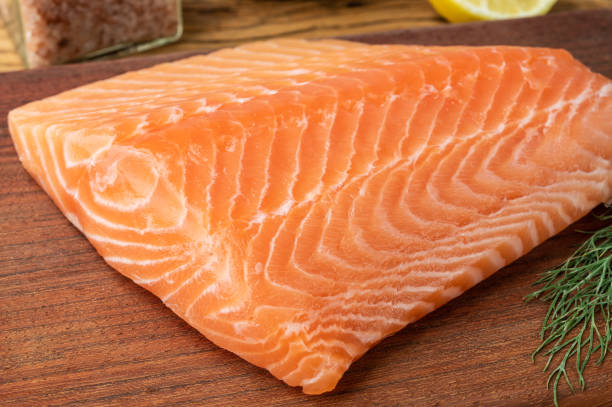 istock Raw salmon fillet with dill over wooden board 1396490706