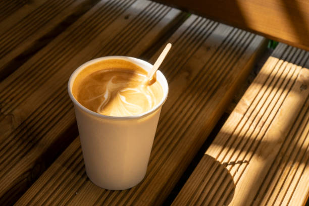 coffee paper cup with a flat white and sun shine on wood boards - hot chocolate latté coffee cappuccino imagens e fotografias de stock