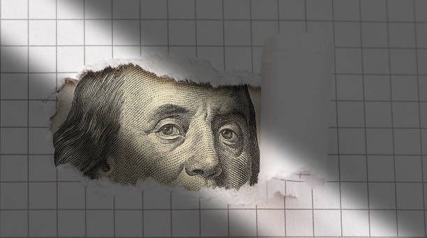 istock Benjamin Franklin peers through torn white paper. Concept. 1396494065