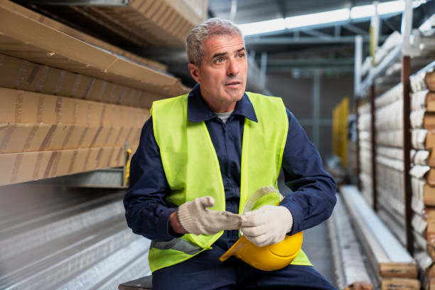 istock Adult male warehouse worker taking off work gloves while taking a break from work 1396495734