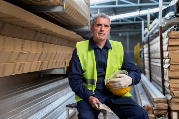 istock Adult male warehouse worker holding protective helmet while looking at the camera 1396495745