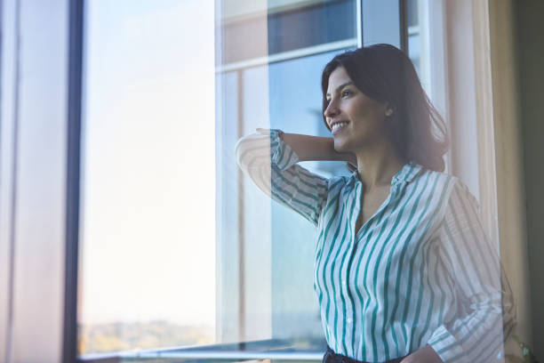 istock Side view portrait of smiling young executive looking out the window inside her office 1396495782