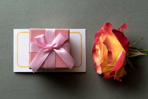 Pink gift box and  blossom rose. Celebration concept, greeting objects flat lay
