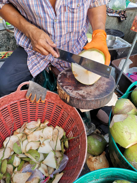 istock Hand man peeling coconut with knife 1396497793