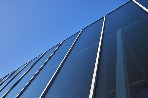 detail of the structure of a glass, steel and concrete facade, in a modern building with blue sky