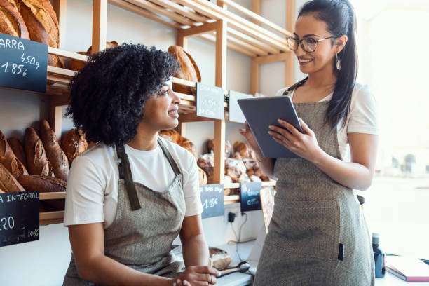 istock Couple women owners bakery working while analyzing report for order delivery with digital tablet in a pastry shop. 1396498517