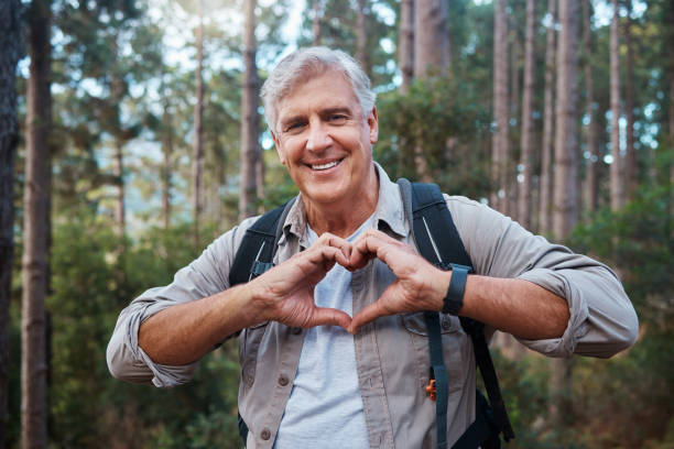 ujęcie dojrzałego mężczyzny kształtującego kształt serca dłońmi podczas wędrówki - senior adult mountain hiking recreational pursuit zdjęcia i obrazy z banku zdjęć