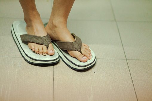 Feet of young thai women in too big sandals