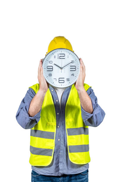 istock Worker with a funny attitude, helmet and yellow vest holding a large clock on a white background, expresses concepts related to workers' rights, rest time and overtime. 1396505184