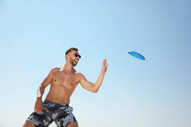 istock Happy man catching flying disk against blue sky on sunny day 1396506076