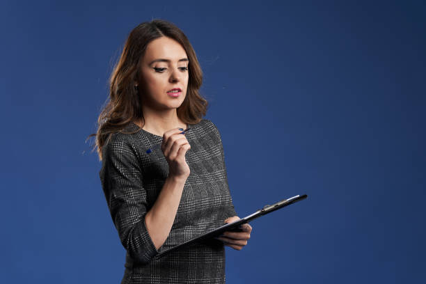 istock Young businesswoman with clipboard on blue background 1396506561