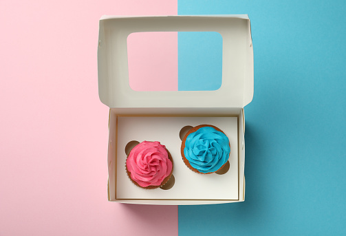 Box with different delicious cupcakes on color background, top view