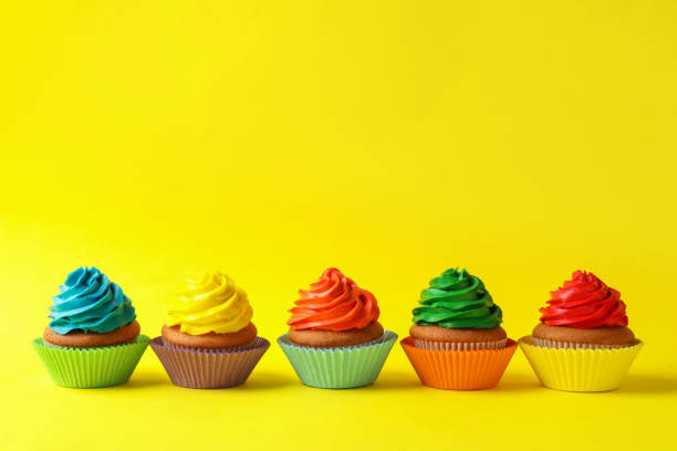 istock Delicious colorful cupcakes on yellow background. Space for text 1396507290
