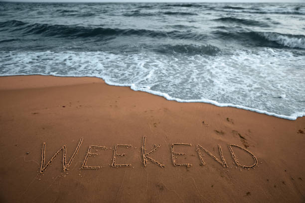 istock Sea wave rolling onto sandy beach with written word Weekend 1396509361