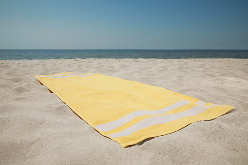 Yellow beach towel on sand near sea