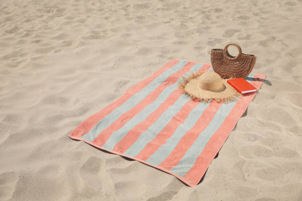 istock Beach towel with bag, hat and book on sand 1396510171