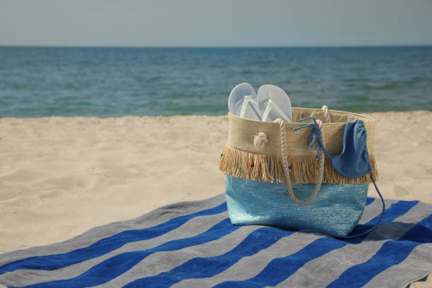 istock Beach towel with bag, flip flops and swimsuit on sand 1396510220