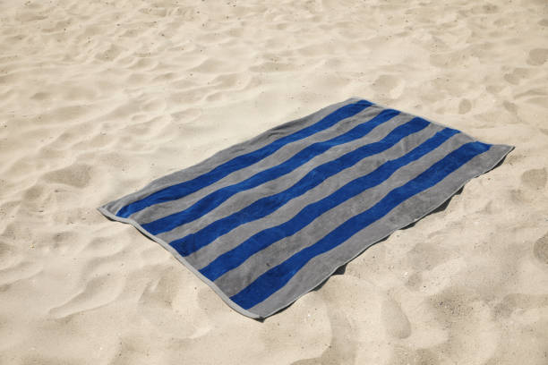 istock Grey and blue striped beach towel on sand 1396510227