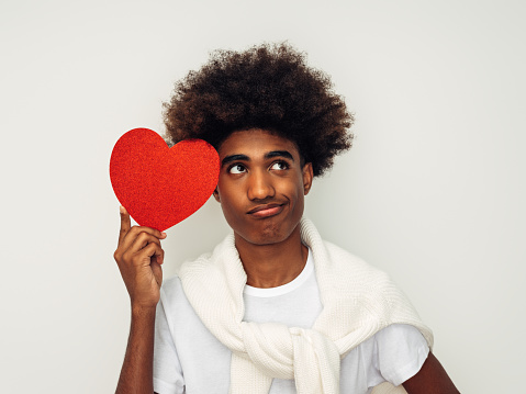 Emotional african american man with african hairstyle holding artificial heart