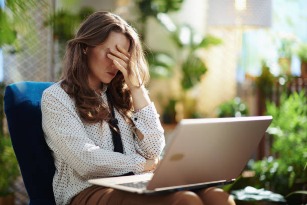 stressed trendy woman in sunny day using laptop stock photo