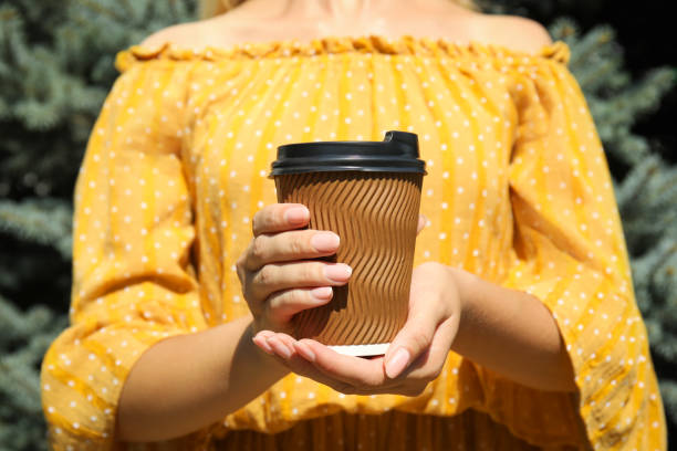 istock Woman holding takeaway cardboard coffee cup with plastic lid outdoors, closeup 1396512892