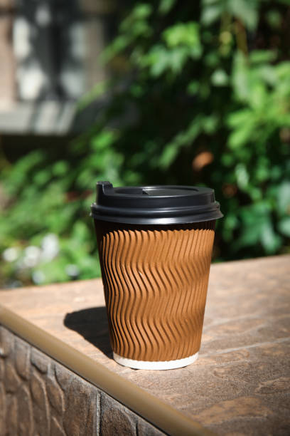 istock Takeaway cardboard coffee cup with plastic lid on stone surface outdoors 1396512928