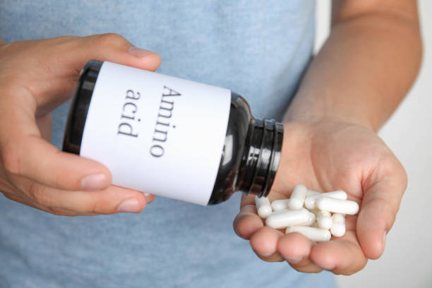 istock Man with amino acids pills on light background, closeup 1396513320