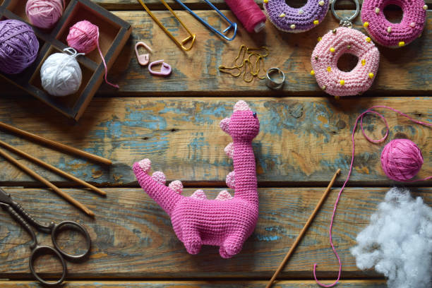 istock Crochet pink dinosaur. Making toy for child. On table threads, needles, hook, cotton yarn. Handmade crafts. DIY concept. Small business. Income from hobby 1396514778
