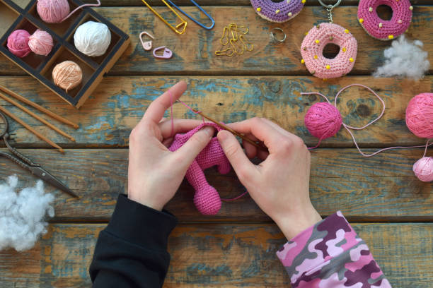 Crochet pink dinosaur. Making toy for child. On the table threads, needles, hook, cotton yarn. Step 1 - knit all details of toy. Handmade crafts. DIY concept. Small business. Income from hobby