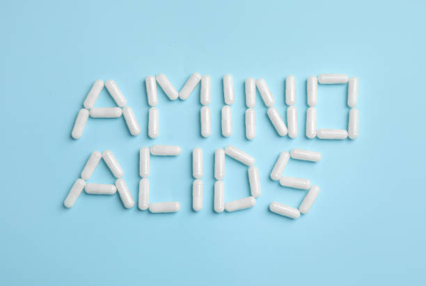 istock Phrase Amino acids made of pills on light blue background, flat lay 1396515076