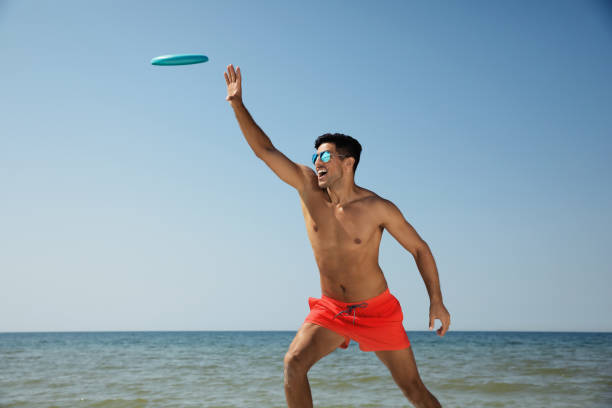 istock Happy man catching flying disk at beach on sunny day 1396515652