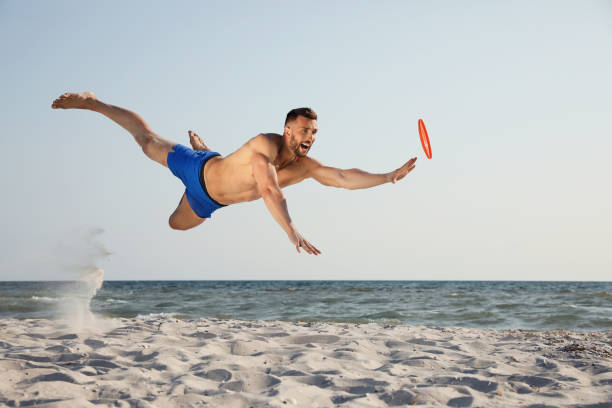 istock Sportive man jumping while trying to catch flying disk at beach 1396515655