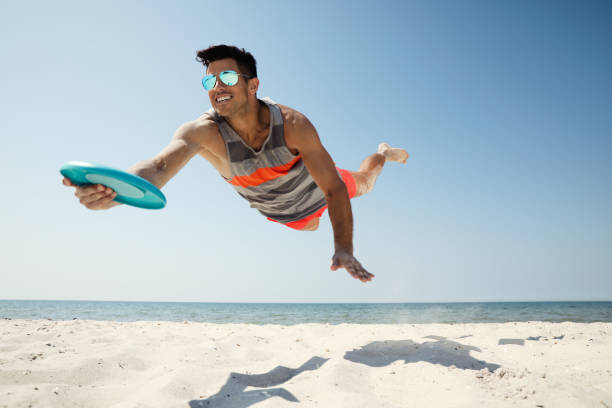 istock Sportive man jumping and catching flying disk at beach 1396515669