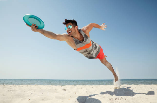 istock Sportive man jumping and catching flying disk at beach 1396515673