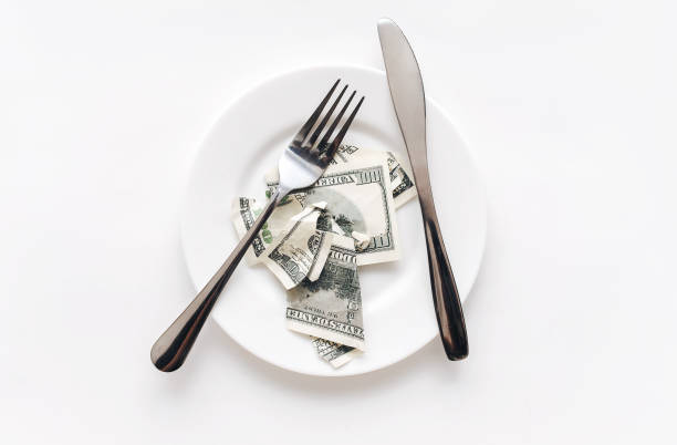 istock A torn hundred-dollar bill lies on a ceramic plate between a fork and a knife on a white tablecloth. The concept of business lunch, banking, life rentier and financial well-being. 1396516898