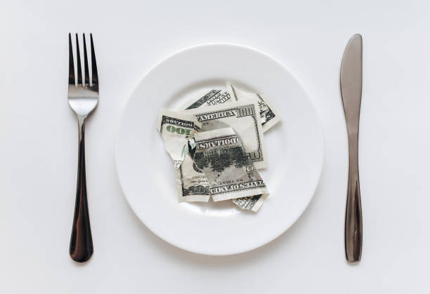 istock A torn old hundred-dollar bill lies on a ceramic plate between a fork and a knife on a with tablecloth. The concept of business lunch, banking, life rentier and financial well-being. 1396516903