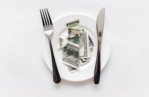 istock A few torn hundred-dollar bill lies on a ceramic plate between a fork and a knife on a white tablecloth. The concept of business lunch, banking, life rentier and financial well-being. 1396518113