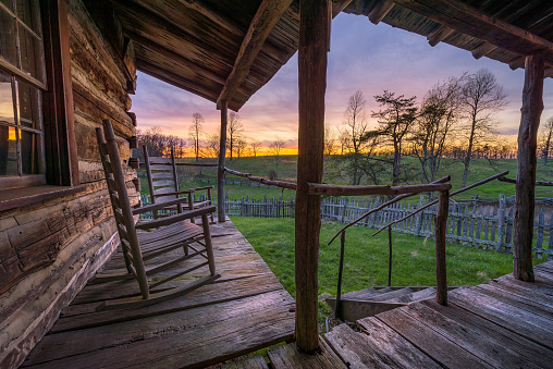 Sunset view over sweeping meadow from the porch of an old rustic cabin in the Cumberland Gap National Park