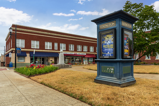 Lexington, NC, USA-8 May 2022:  Kiosk showing informational posters of  cultural events sets in front of vintage buildings and businesses in small commons area.