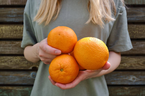oranges fraîches dans les mains d’une fille. agricultrice récoltant des oranges naturelles douces. fruits biologiques sains cueillis à la main avec des vitamines. délicieux agrumes tropicaux juteux - grapefruit citrus fruit water fruit photos et images de collection