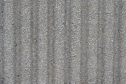 the textured texture of a concrete wall to small stones with vertical lines.