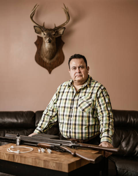 istock Mature Latin man posing with guns and hunting trophy 1396533508