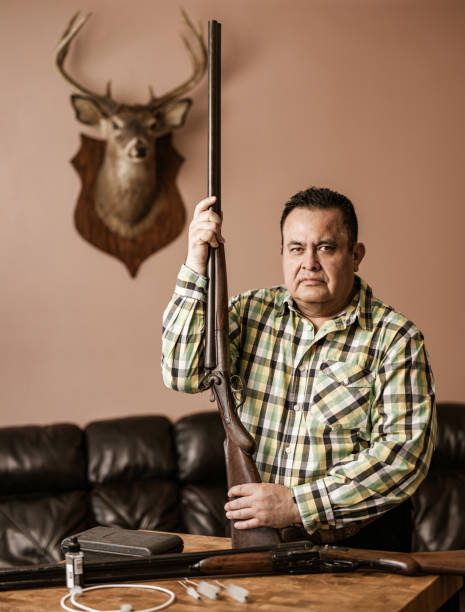 istock Mature Latin man posing with guns and hunting trophy 1396533512
