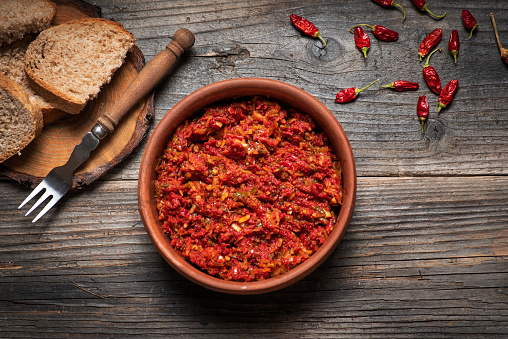 Spread of cooked red dried peppers in a bowl on a wooden background